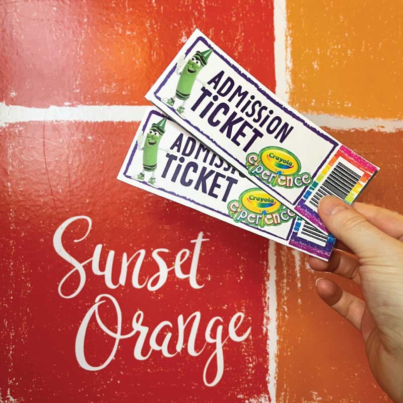 Two tickets held up next to Sunset Orange